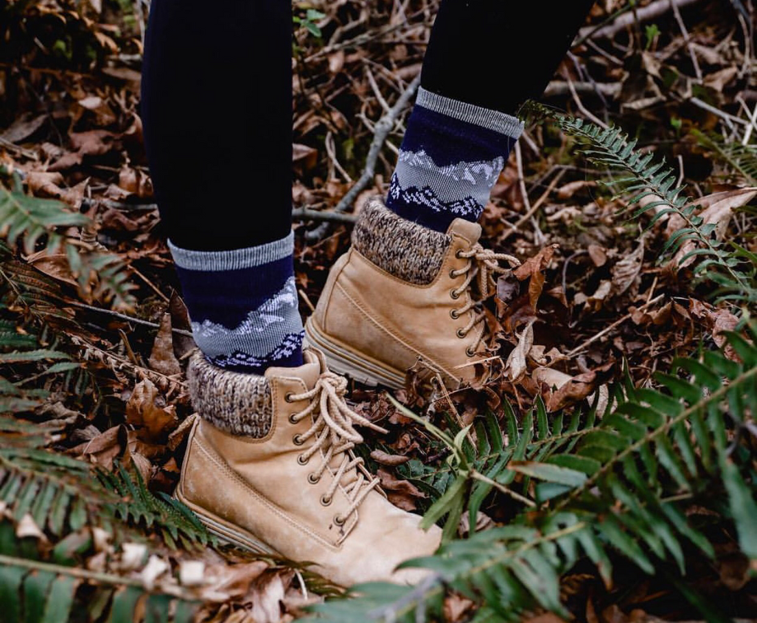 Pictured is a photo of a person's feet wearing hiking boots and Wul's merino wool socks.